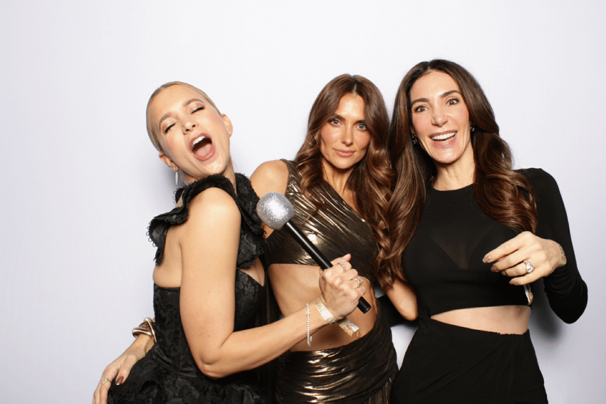 Three women enjoying a selfie booth session, capturing fun and unforgettable memories at a party, featuring instant prints.