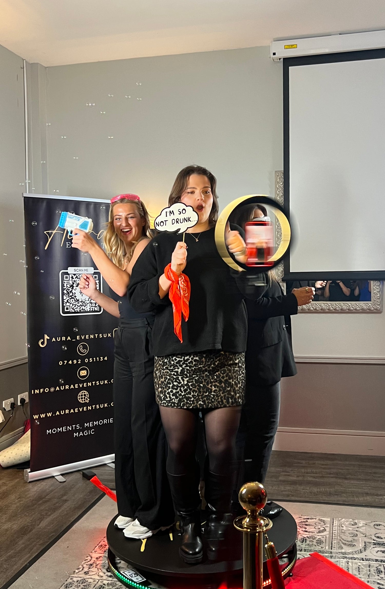 Picture of the behind the scenes of our 360 photo booth with aura events logo in background