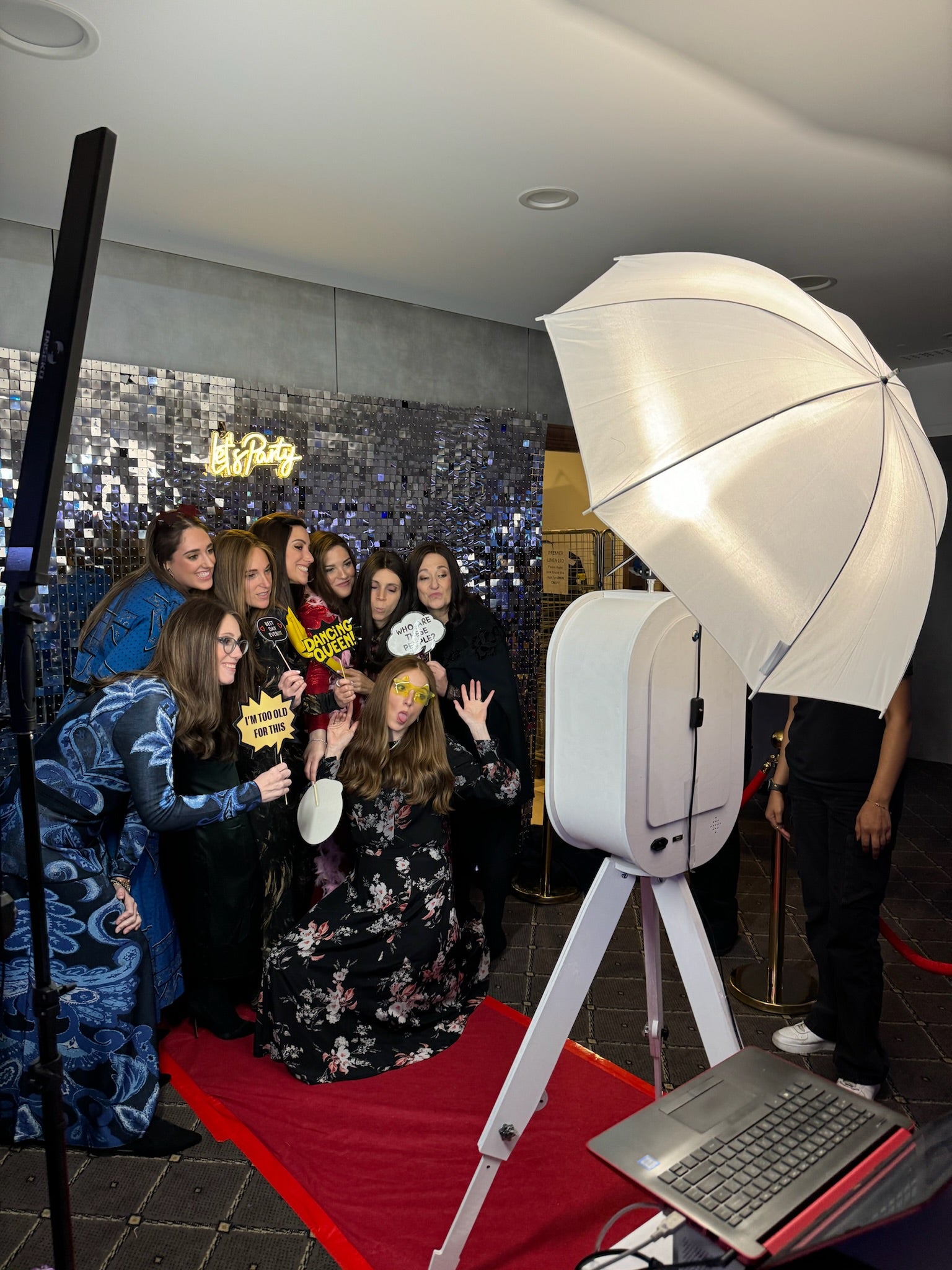 Behind the scenes of a corporate event. Guests posing inf ront of silver backdrop for a photo on our selfie photo booth.